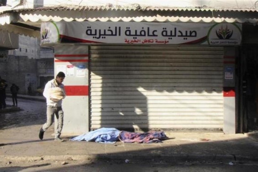A man carrying bread walks past covered dead bodies lying on the ground after what activists said was an air raid by forces loyal to Syrian President Bashar Al-Assad, at Masaken Hanano in Aleppo, December 22, 2013.