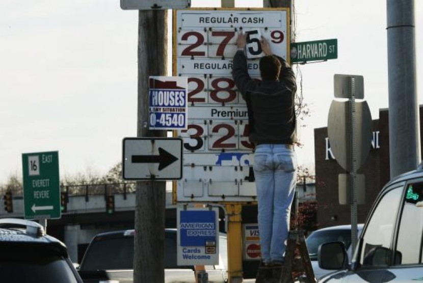 Seorang petugas pompa bensin mengganti papan harga minyak di sebuah pompa bensin di Medford, Massachusetts, pada 4 Desember 2014. 