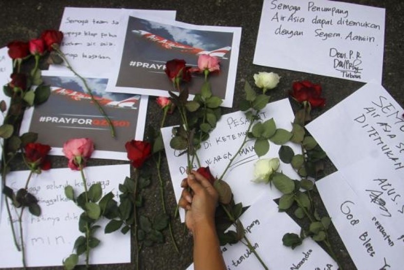 A man places flowers down as a sign of respect to Air Asia QZ 8501 passengers in Batu, East Java province, December 30, 2014
