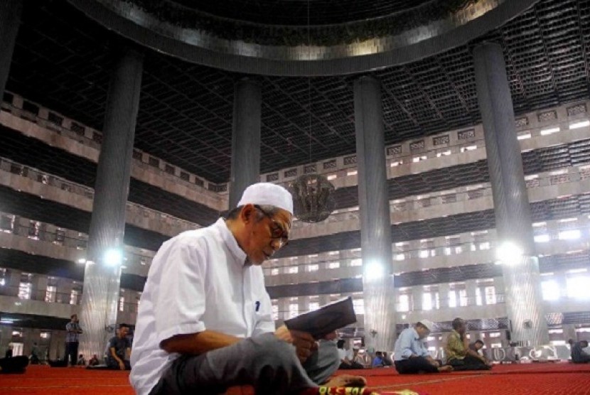 A man recites Quran after noon praying at Istiqlal.   