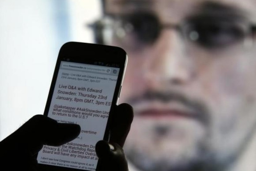A man uses his cell phone to read updates about former US spy agency contractor Edward Snowden answering users' questions on Twitter in this photo illustration, in Sarajevo, January 23, 2014.