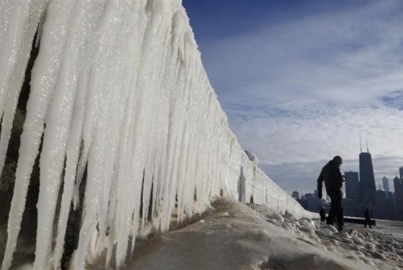 A man walks beside a frozen wall on a beach in Chicago, Illinois, January 7, 2014.