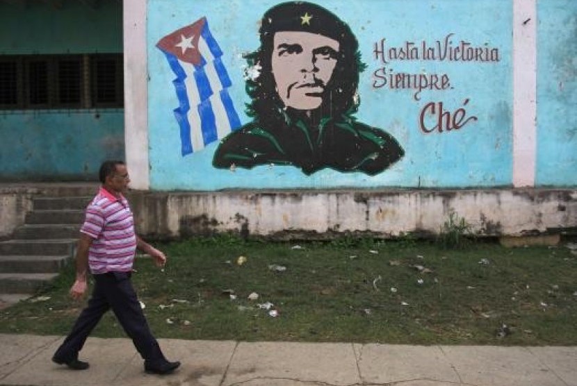 Seorang pria berjalan melewati lukisan pahlawan revolusi Ernesto 'Che' Guevara di Havana, Kuba.