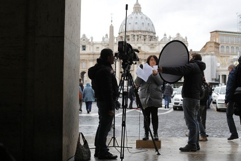 A media correspondent gives her report in Rome, as Saint Peter's Basilica at the Vatican is seen in the background February 11, 2013. 