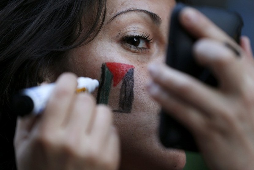 A supporter of Palestine draw Palestinian's flag on her cheek.
