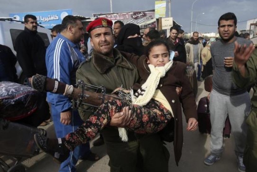 A member of the Palestinian security forces carries a girl, who needs to receive medical treatment outside Gaza, as she waits to cross into Egypt at the Rafah crossing between Egypt and the southern Gaza Strip December 21, 2014. 