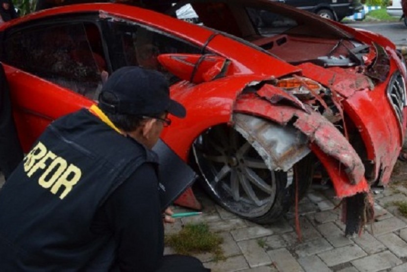 A member staff of Surabaya Police Department forensic laboratories examines the ferrarri-like electric car which Minister Dahlan Iskan drove before the crash. the car is now in Magetan police office, East Java.   