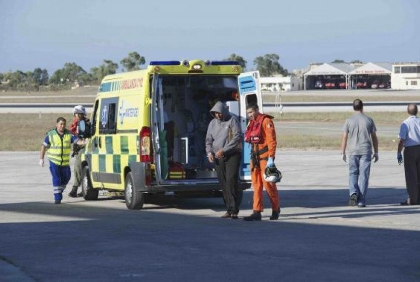 A migrant is helped by an Armed Forces of Malta (AFM) airman to a waiting ambulance at the Air Wing base outside Valletta in this handout taken September 14, 2014.