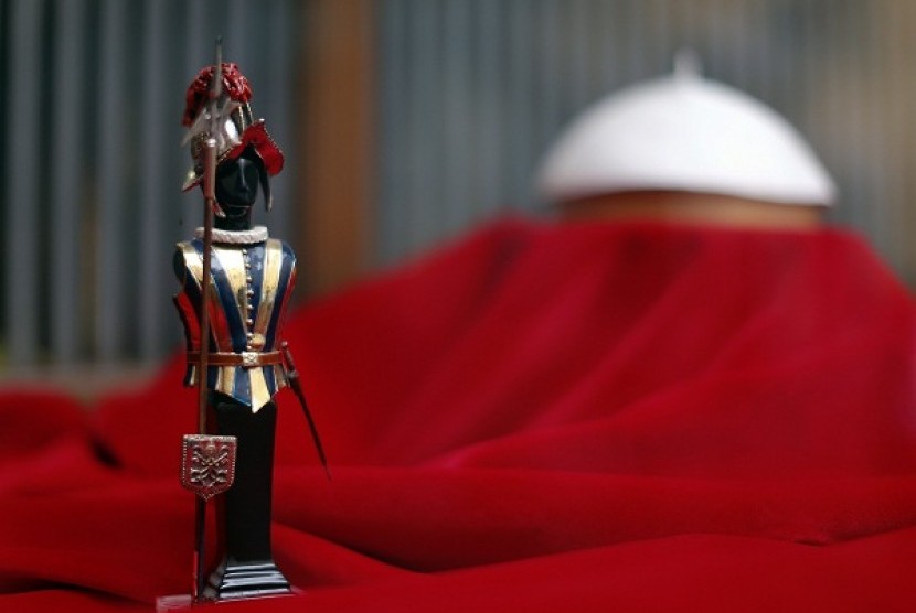 A model of a Swiss guard is seen next to a Papal white skull cap in the Gammarelli's tailor shop window in Rome March 8, 2013. Roman Catholic cardinals will vote later on Friday on when to start a conclave to elect a successor to Pope Benedict.