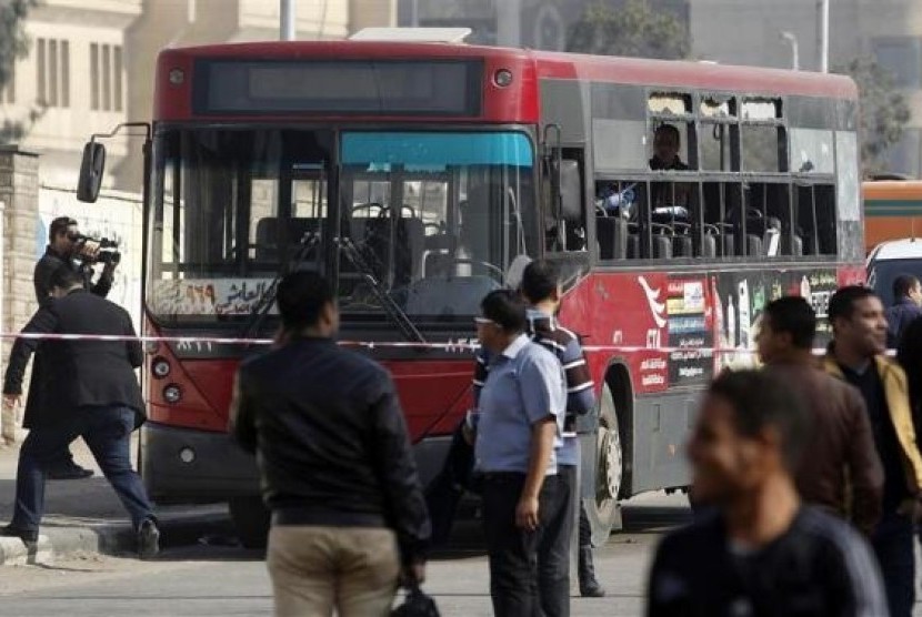 A of the media films a damaged bus after a bomb blast near the Al-Azhar University campus in Cairo's Nasr City district December 26, 2013.