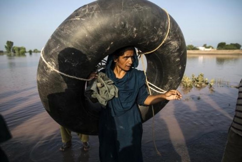 A Pakistani woman carries a rubber ring as she stands beside a flooded field following heavy rain in Cheniot, Punjab Province September 9, 2014.