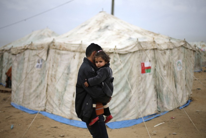A Palestinian man carries his sister near tents erected by Palestinians whose houses were destroyed by what witnesses said was Israel shelling during a 50-day conflict last summer, east of Khan Younis in the southern Gaza Strip January 27, 2015. The main U