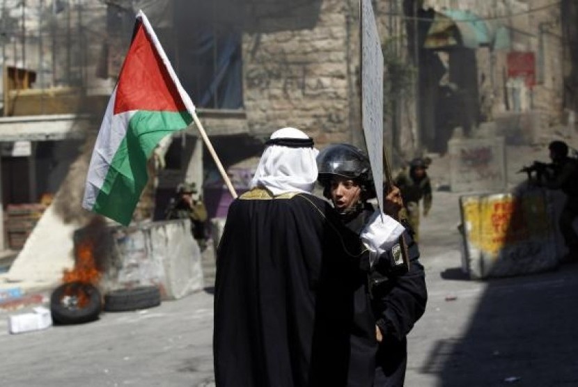 A Palestinian man holding a Palestinian national flag argues with an Israeli policewoman, during a protest against the Israeli offensive in Gaza, in the West Bank city of Hebron August 22, 2014.