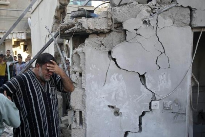 A Palestinian man reacts as he stands next to the wreckage of a house, which witnesses said was destroyed in an Israeli air strike that killed at least nine members from the al-Ghol family, in Rafah, August 3, 2014.