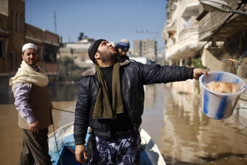 A Palestinian policeman carries a bucket containing food supplies, to be passed to people whose homes were flooded with rainwater, in the northern Gaza Strip December 15, 2013. 