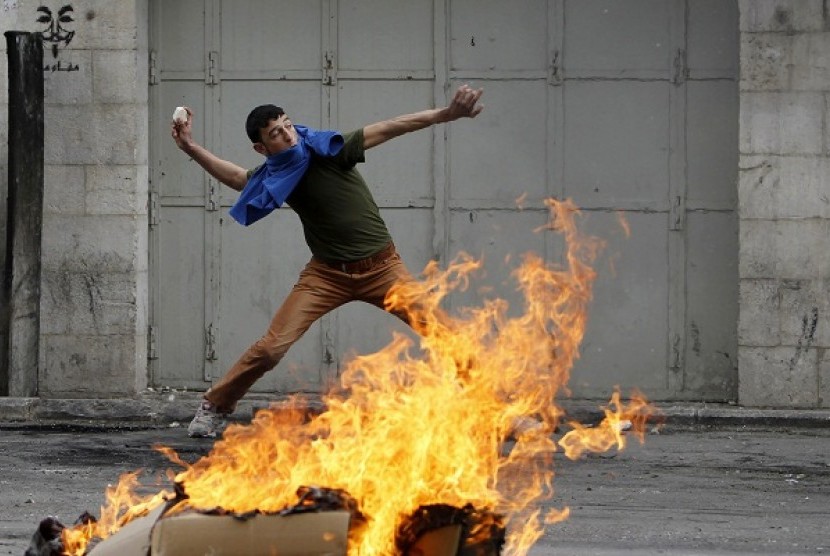 A Palestinian protester throws a stone during clashes with Israeli soldiers and border policemen in the West Bank city of Hebron on Sunday. The death in an Israeli jail of a Palestinian detainee on Saturday and an on-going hunger strike by four inmates hav