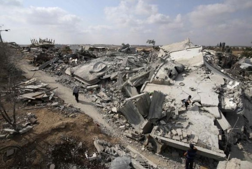 A Palestinian woman walks past the ruins of houses which witnesses said were destroyed during the Israeli offensive in Johr El-Deek village near the central Gaza Strip August 17, 2014.