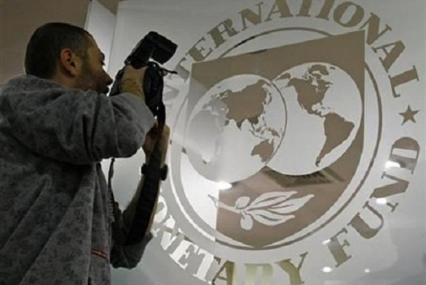 A photographer takes pictures through a glass carrying the International Monetary Fund (IMF) logo.