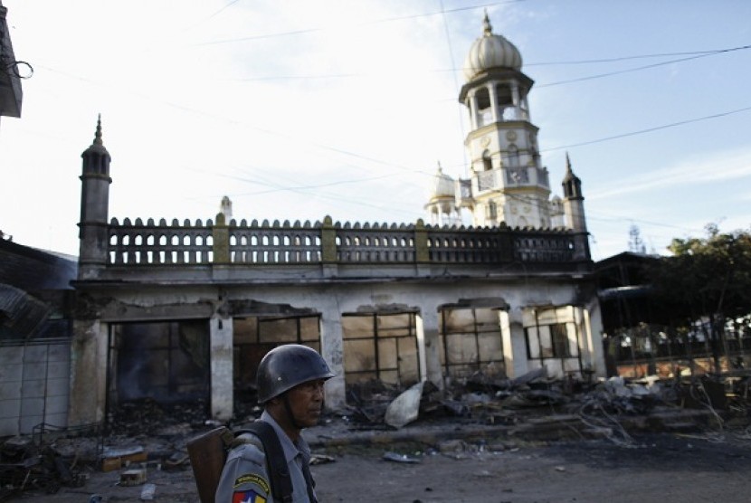 A police officer stands near a mosque which was burnt during a riot between Buddhist and Muslims in Lashio township May 29, 2013. 