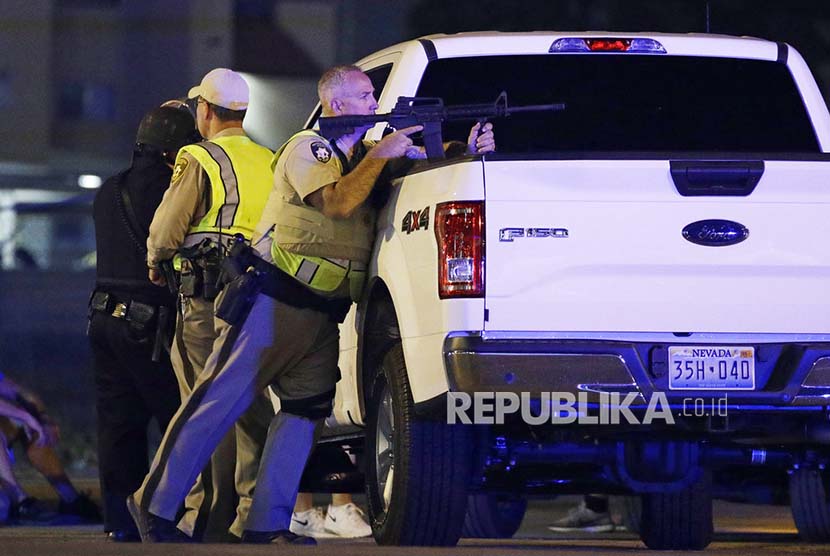 Polisi setempat berlindung dari balik mobil di dekat  Mandalay Bay, Las Vegas Strip, Ahad (1/10) waktu setempat.