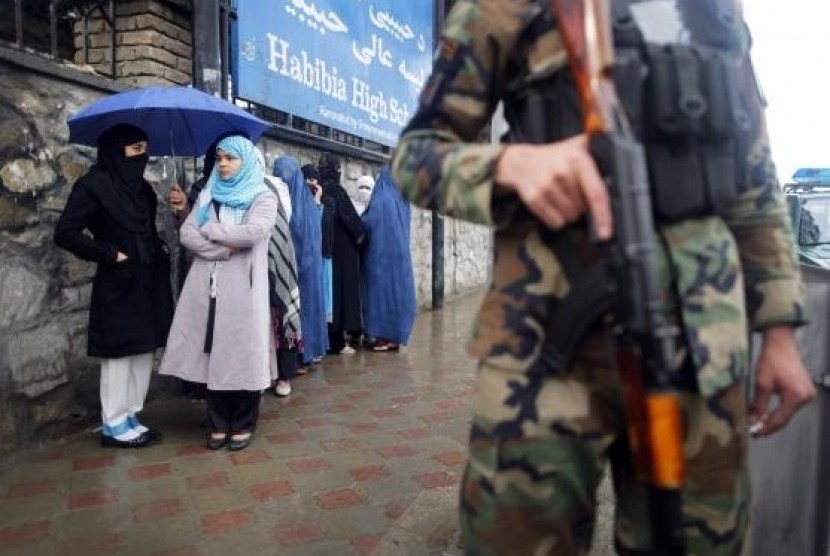 A policeman stands guard outside a polling station in Kabul as Afghans wanting to vote queue outside before it opened April 5, 2014.