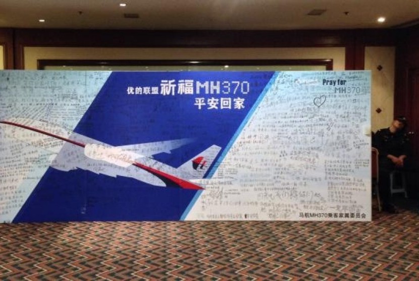 A policeman takes a nap beside a board written with messages for passengers onboard the missing Malaysia Airlines Flight MH370 in Beijing May 2, 2014.