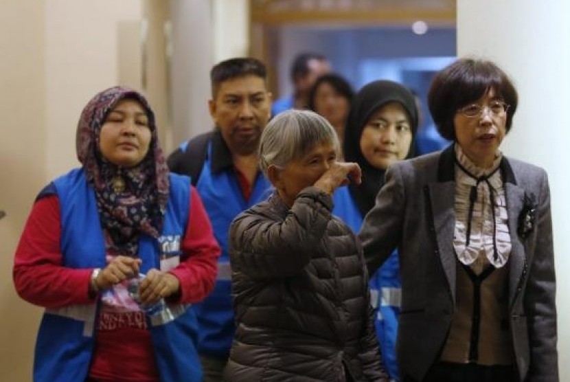 A relative (center) of a passenger aboard Malaysia Airlines MH370 reacts as she enters a meeting room with volunteers from Malaysia (in blue vests) at the Lido Hotel in Beijing March 27, 2014. 