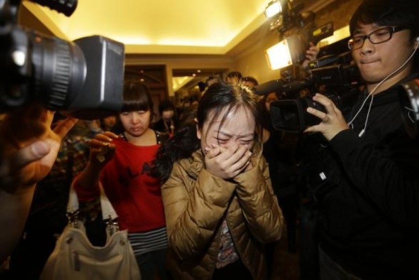 A relative (front) of a passenger of Malaysia Airlines flight MH370 cries as she walks past journalists at a hotel in Beijing March 9, 2014. 