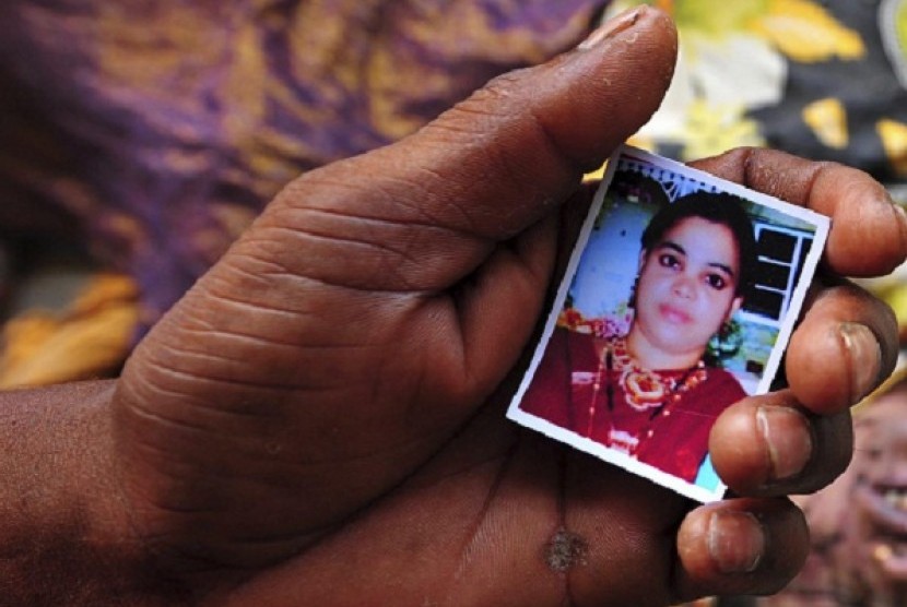 A relative holds a picture of a missing woman in front of the body of a garment worker who died in the collapse of the Rana Plaza building, in Savar, 30 km (19 miles) outside Dhaka April 25, 2013. 