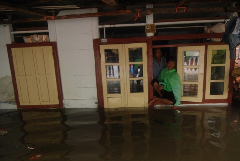 A residence keeps staying despite floods inundated their house in Manado, North Sulawesi, on Sunday.  