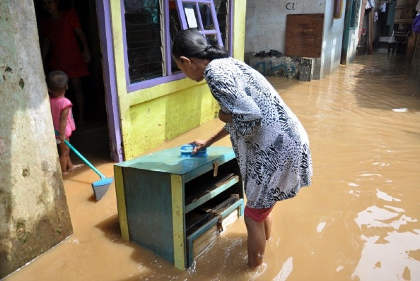 A resident use flood water to clean her furniture covered with mud from the previous flood in Kampung Melayu, East Jakarta. on Friday.  