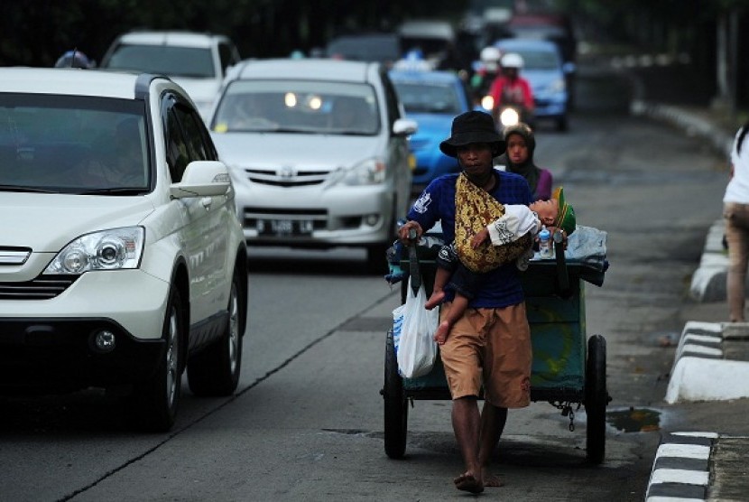 A scavenger pulls his cart while holds his child in Jakarta. Head of National Family Planning Coordinating Board (NFPCB) says that uncontrolled population growth may impact on many aspects of life, including problems in the economy and welfare. (illustrati