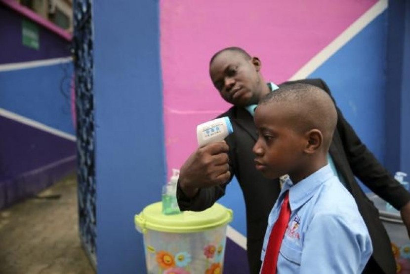 A school official takes a pupil's temperature using an infrared digital laser thermometer in front of the school premises, at the resumption of private schools, in Lagos in this September 22, 2014 file photo.