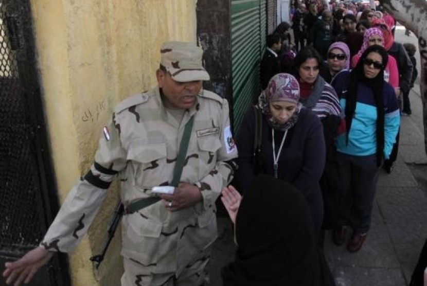 A soldier stands guard as women queue outside a polling center to vote in a referendum on Egypt's new constitution in Cairo January 14, 2014. 