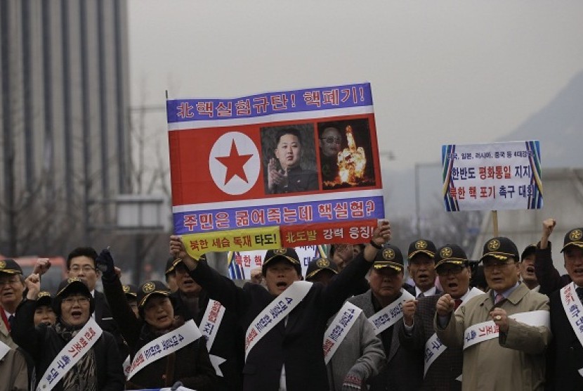 A South Korean protester holds a poster with photos of North Korean leader Kim Jong Un and late leader Kim Jong Il with writing reading 