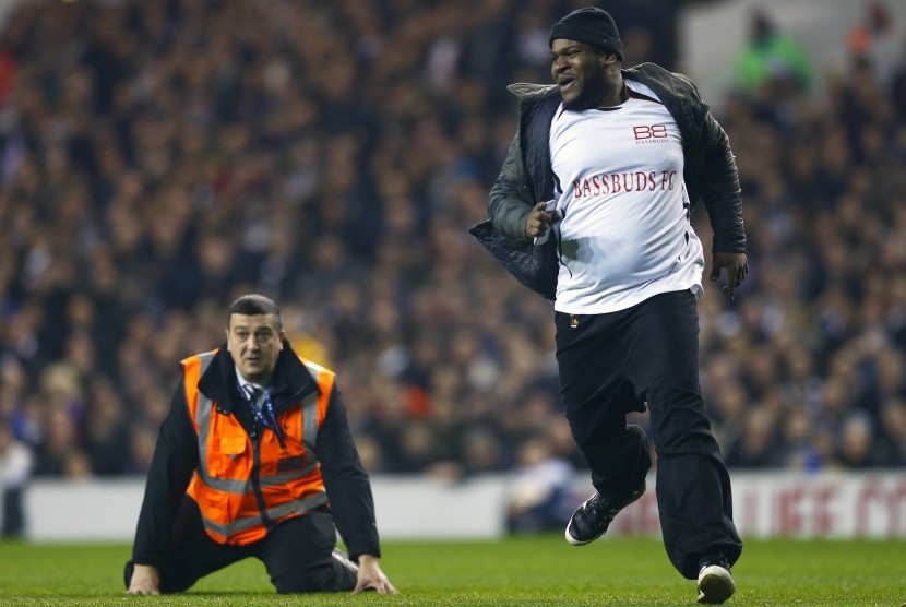 A steward falls over as he tries to catch a spectator that had run onto the pitch during the Europa League soccer match between Tottenham Hotspur' and Partizan Belgrade at White Hart Lane in London November 27, 2014.