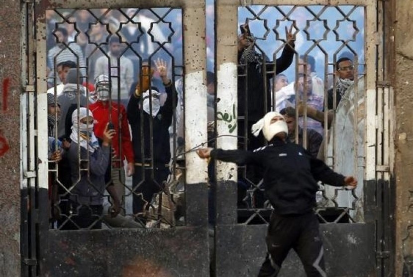 A student of Al Azhar University throws stones as another takes pictures during clashes with riot police and residents of the area at the Al-Azhar University campus in Cairo, on Friday.