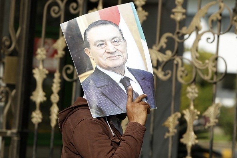 A supporter of Egypt's deposed president Husni Mubarak holds up his picture outside the Maadi Armed Forces hospital, where Mubarak is currently being held, in Cairo January 13, 2013.    