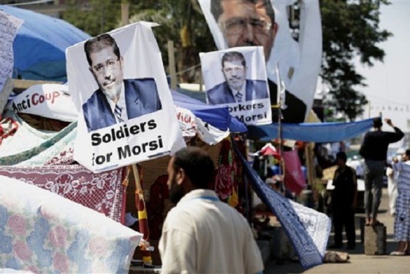 A supporter of Egypt's Islamist President Mohammed Mursi in front pictures of the president at Nasr City, Egypt, Thursday, July 25, 2013. 