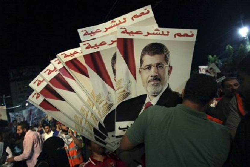 A supporter of Egypt's ousted President Mohammed Morsi holds his posters with Arabic writing which reads 