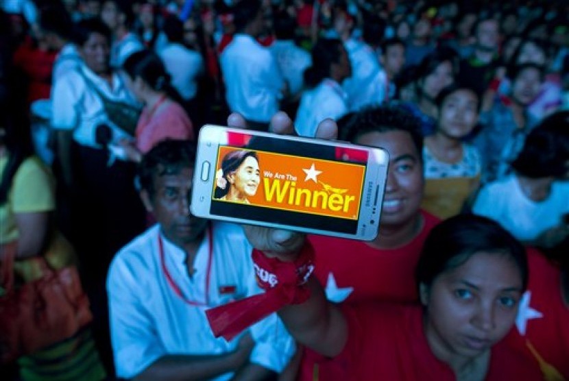 A supporter of Myanmar's National League for Democracy party displays her mobile phone with a picture of Suu Kyi as they gather to celebrate unofficial election results outside the NLD headquarters in Yangon, Myanmar, Monday, Nov. 9, 2015