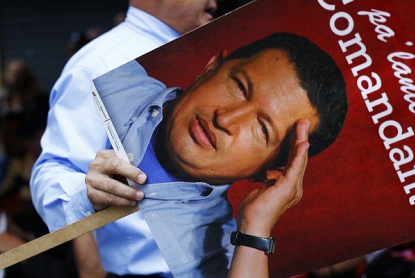 A supporter of Venezuelan President Hugo Chavez holds a picture of him as he takes part in a gathering at Plaza Bolivar in Caracas on Monday.