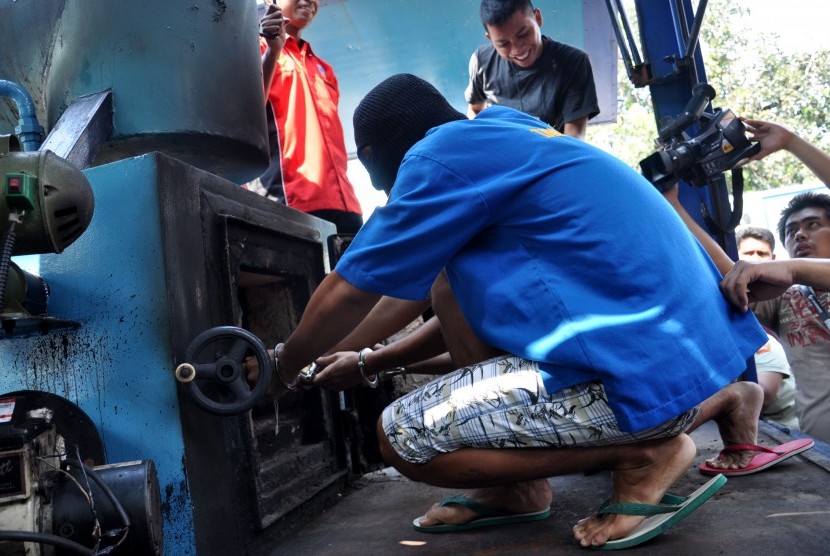 A suspect of meth smuggling puts the confiscated meth into a machine to destroy it in Jakarta on Thursday.