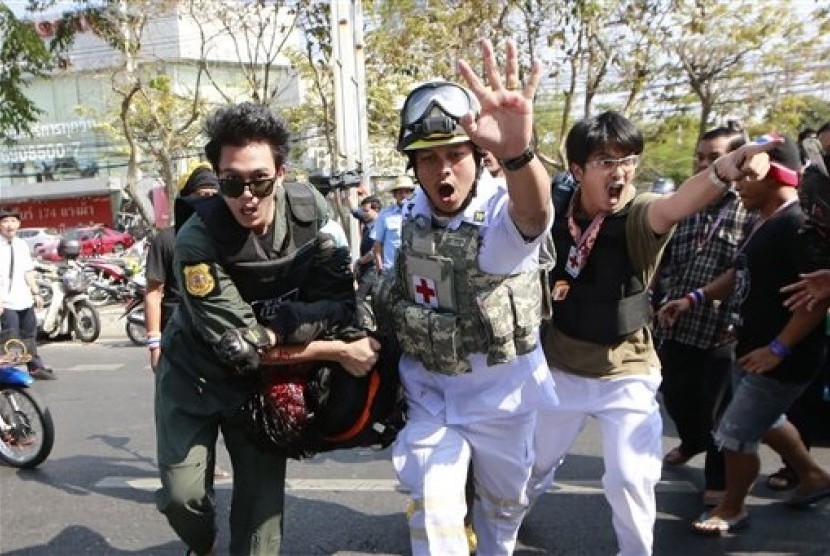 A suspected gunman (center bottom) is carried to an ambulance when he was caught and beaten by anti-government protesters after allegedly firing a pistol at protesters during a rally outside the Army Club Tuesday, Jan. 28, 2014 in Bangkok, Thailand. 