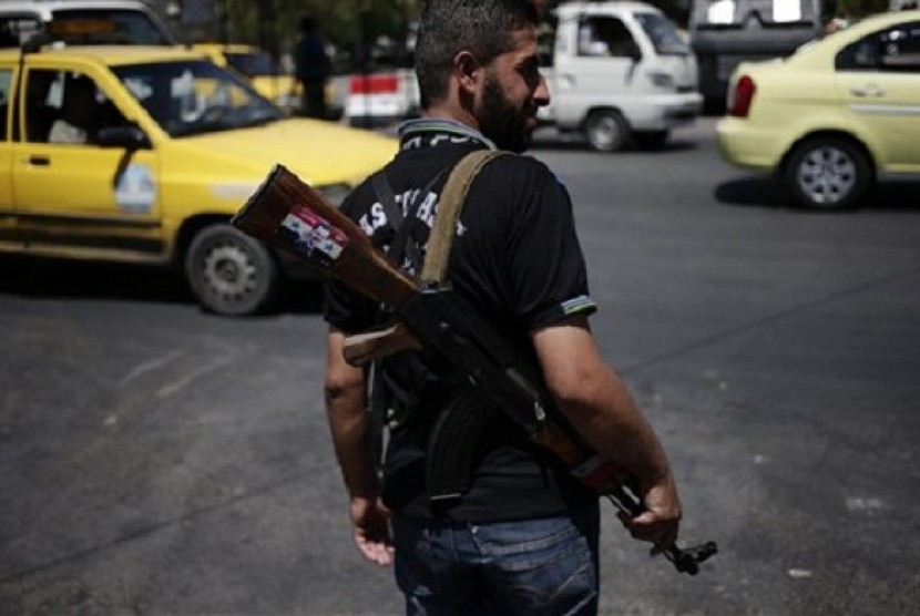 A Syrian military soldier holds his AK-47 with a sticker of Syrian President Bashar Assad and Arabic that reads, 