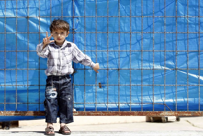 A Syrian refugee boy gestures as he stands in front of the fence at Yayladagi refugee camp in Hatay province near the Turkish-Syrian border on April 17. 