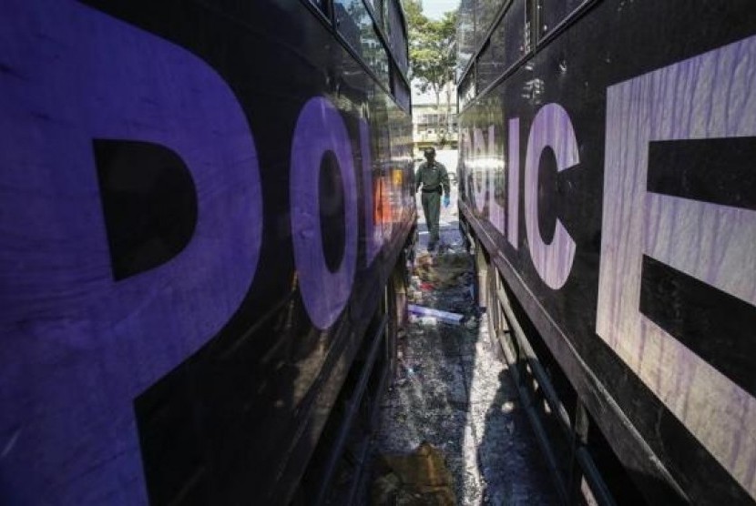 A Thai security personnel inspects destroyed police trucks at the Thai-Japan youth stadium, the site of fierce clashes between anti-government protester and riot police, in central Bangkok December 27, 2013.