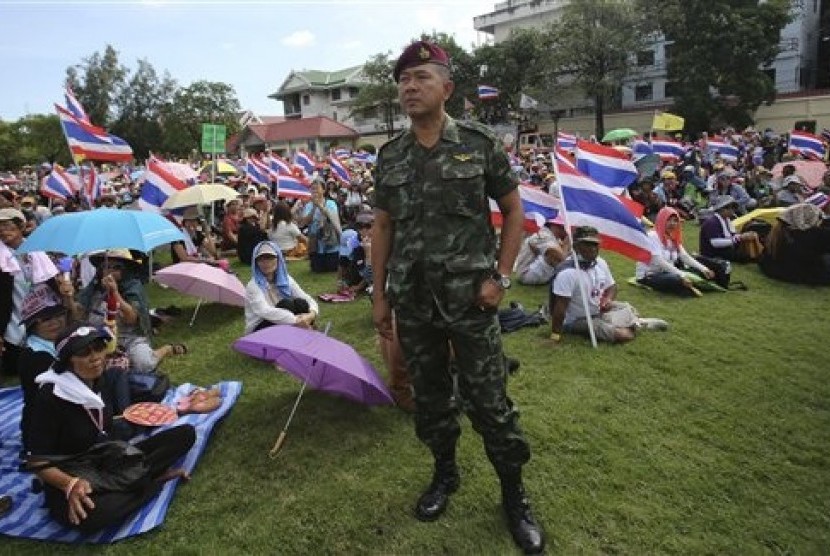 A Thai soldier stands as anti-government protesters sit at the Royal Thai Army compound in Bangkok, Thailand, Friday, Nov. 29, 2013. 