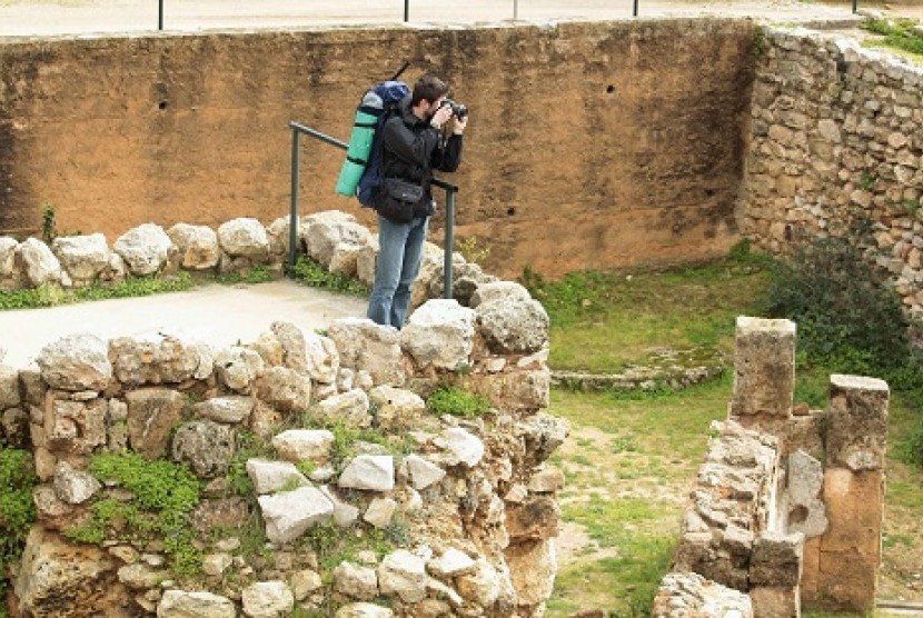 A tourist takes a picture at the archaeological site of Carthage, near Tunis February 10, 2013. Tunisia's tourism industry recorded a sharp drop in activity after the assassination of secular opposition leader Chokri Belaid that has plunged Tunisia deeper into political crisis. 