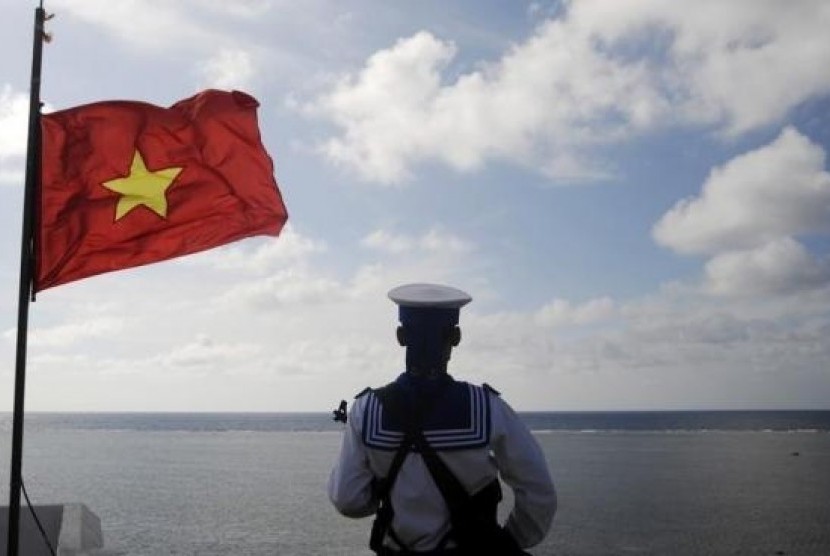 Seorang tentara berdiri di samping bendera Vietnam (ilustrasi).